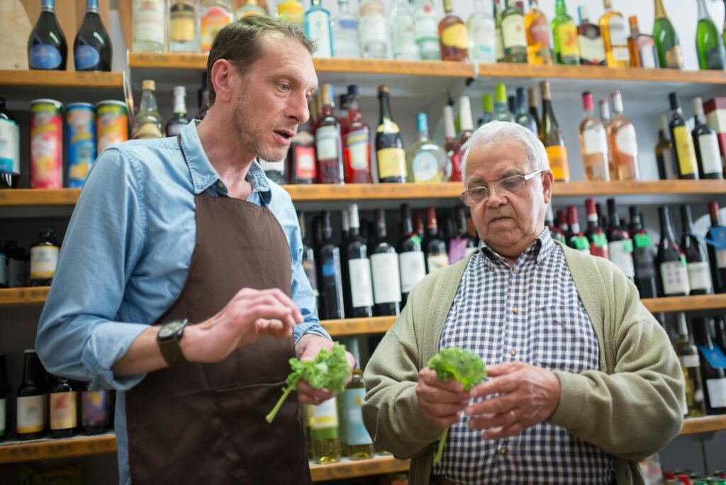 pexels-photo-8422720-8422720 Senior man and store clerk examine fresh lettuce in a Portuguese grocery store.